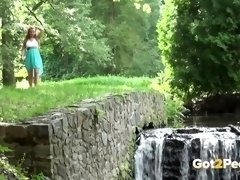 Sexy babe pees near a waterfall